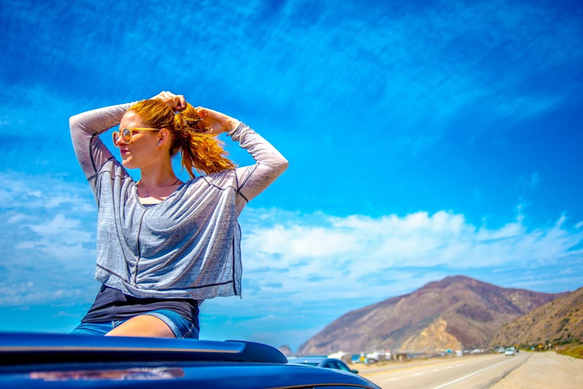 woman in grey and black plaid shirt sitting on car hood during daytime