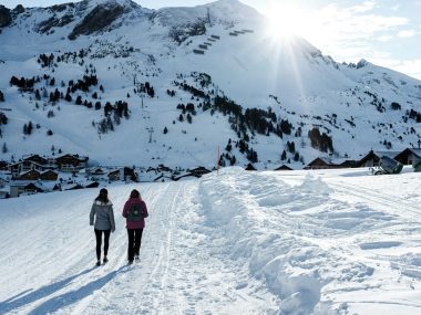 two person walking on snow covered ground during daytime