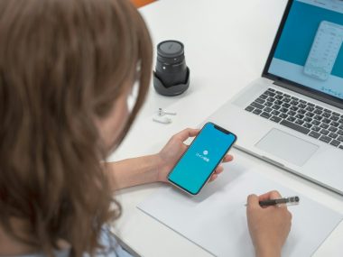 woman holding smartphone while writting