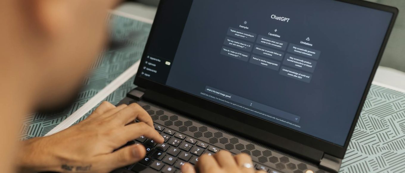 Close-up of a person typing on a laptop displaying the ChatGPT interface, emphasizing modern technology use.