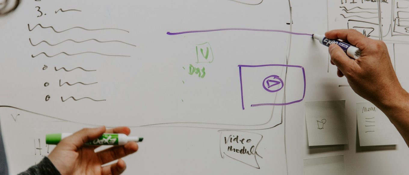 two people drawing on whiteboard