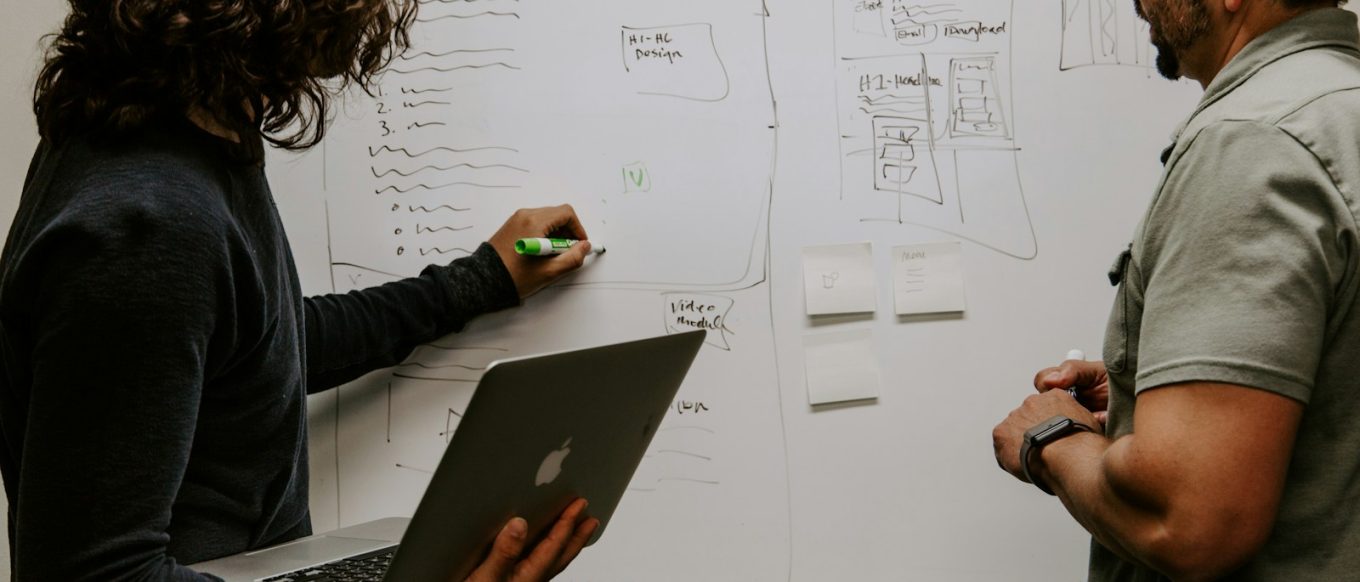 man wearing gray polo shirt beside dry-erase board