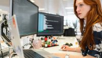 woman in green shirt sitting in front of computer