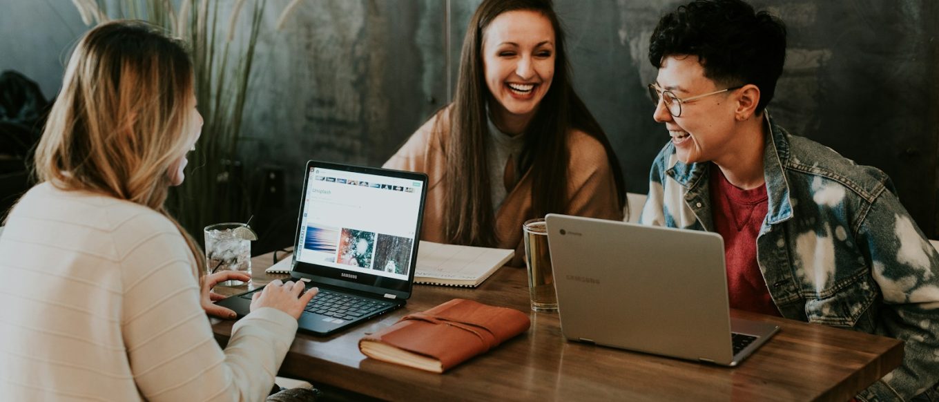 three people sitting in front of table laughing together