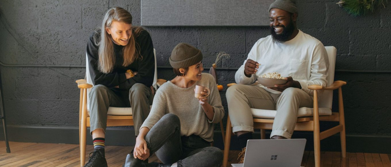 Three coworkers sitting together laughing Surface laptop on furniture