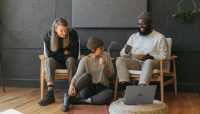 Three coworkers sitting together laughing Surface laptop on furniture