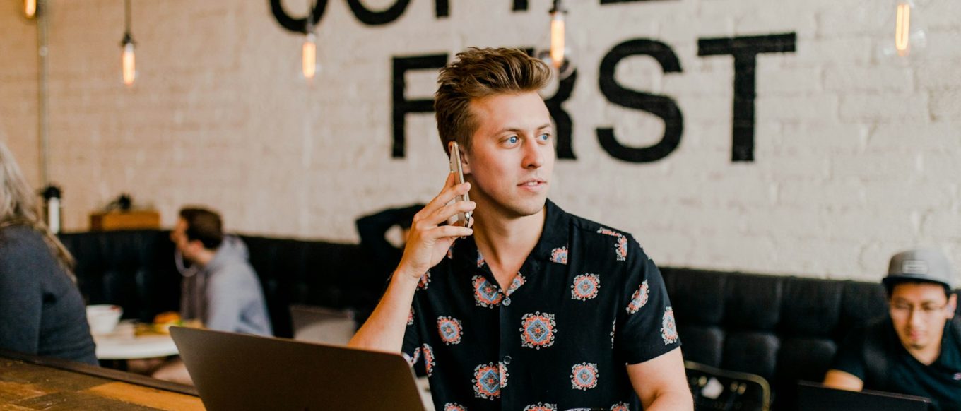 man holding phone white using MacBook